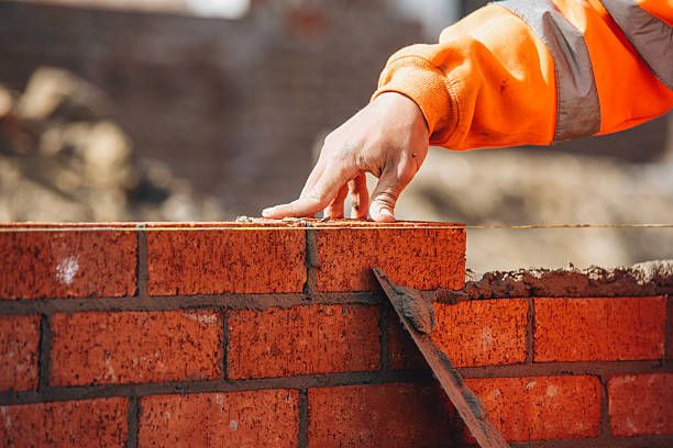 Bricklayer levelling a course on a retaining wall