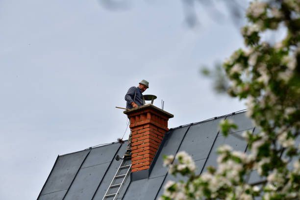 Mason repairing a brick chimney stack from the rooftop